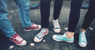 Young rebel teenagers wearing casual sneakers, walking on dirty concrete. Canvas shoes and sneakers on female adults